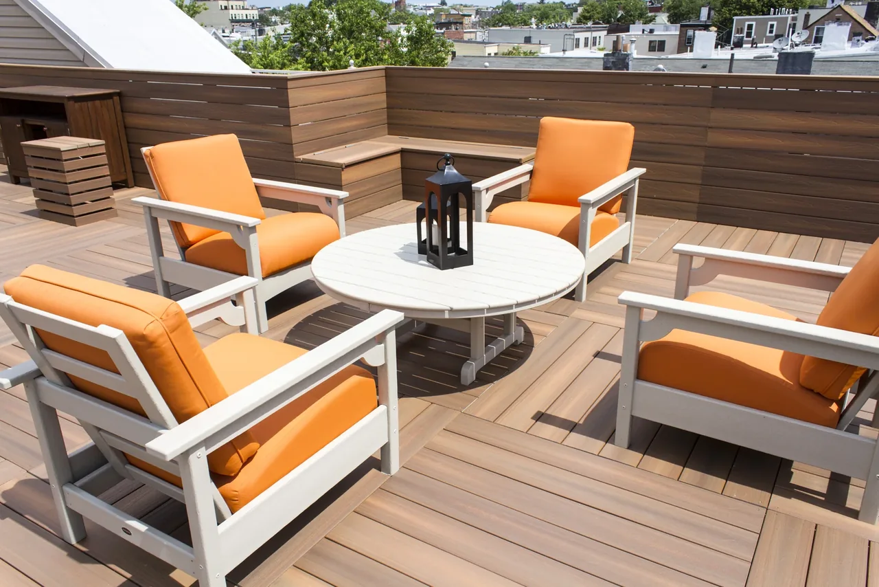 Finished Jersey City Fiberon composite rooftop deck with built-in benches, privacy screening, and orange lounge chairs