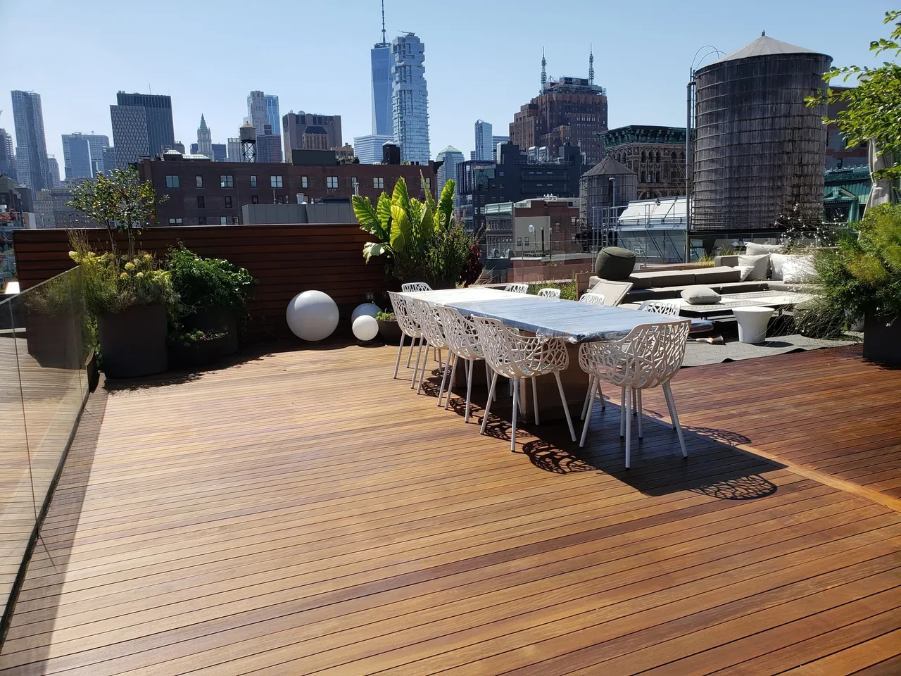Finished rooftop deck with dining, lounge seating, planting, and privacy screening