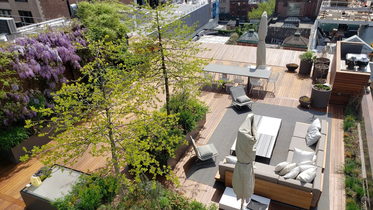 Completed City Decks rooftop with wood decking, built-in seating, planting, and an outdoor dining area