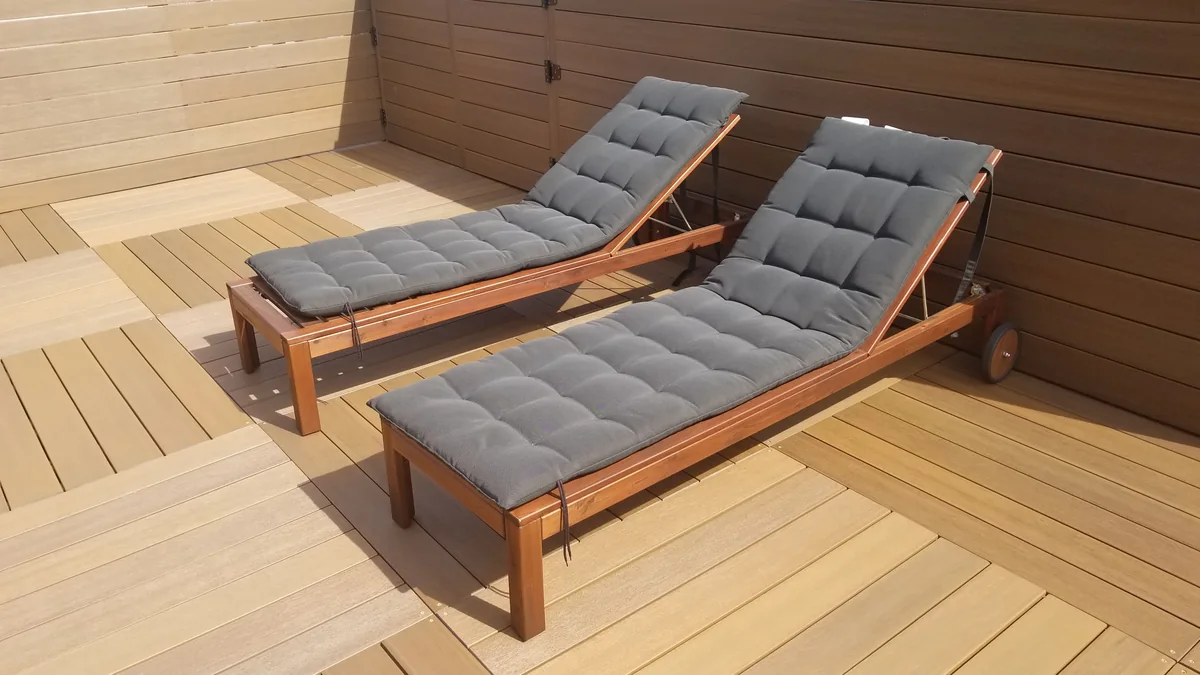 Modular rooftop deck with two gray-cushion loungers and privacy screening