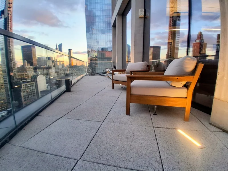Paving and lounge seating beside a glass railing.