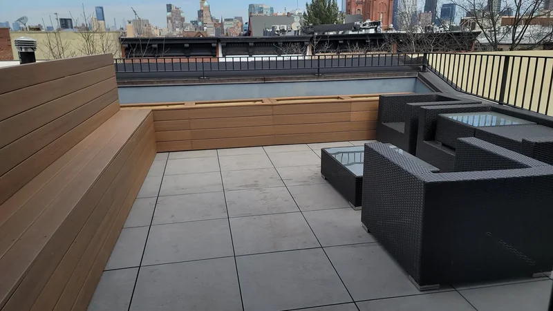 Planters and privacy screening create a defined edge beside a paved lounge.